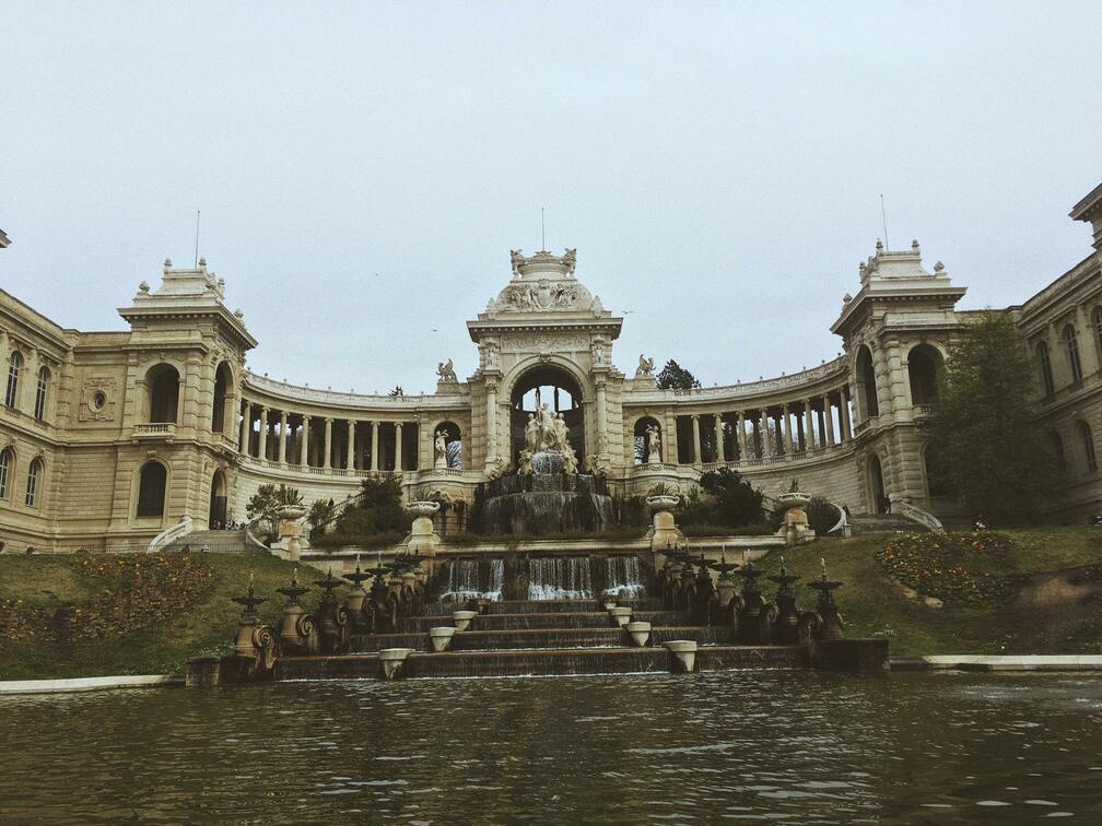 une fontaine en escaliers devant un grand bâtiment du parc Longchamp